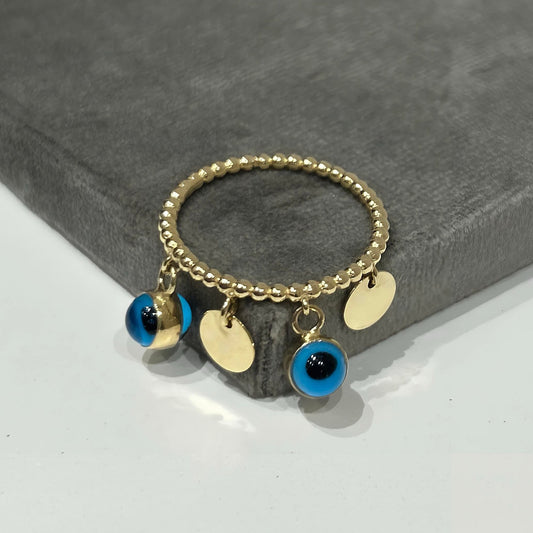 14K gold beaded ring with dangling evil eye and gold disc charms, on gray velvet display