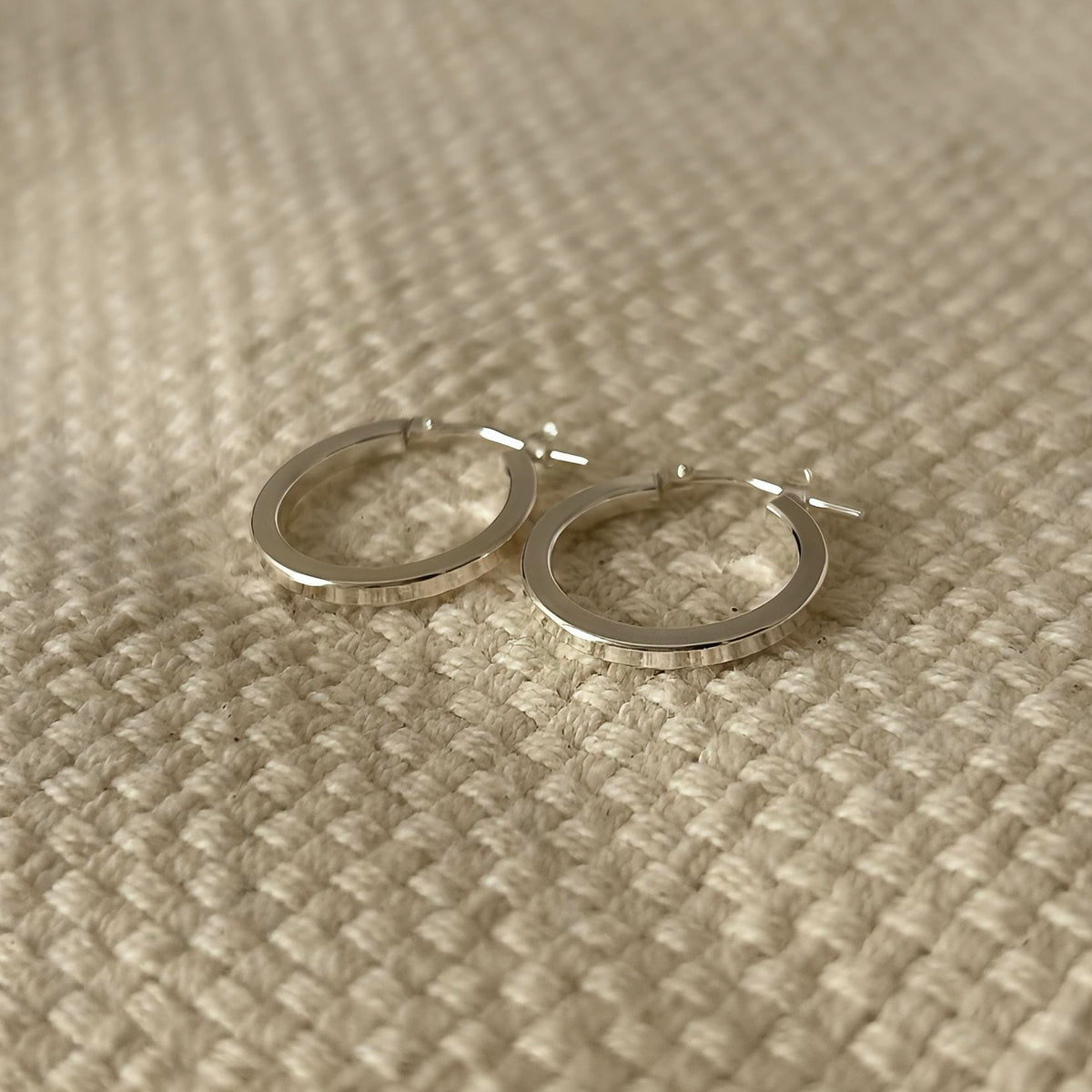 Pair of polished silver hoop earrings, close-up detail