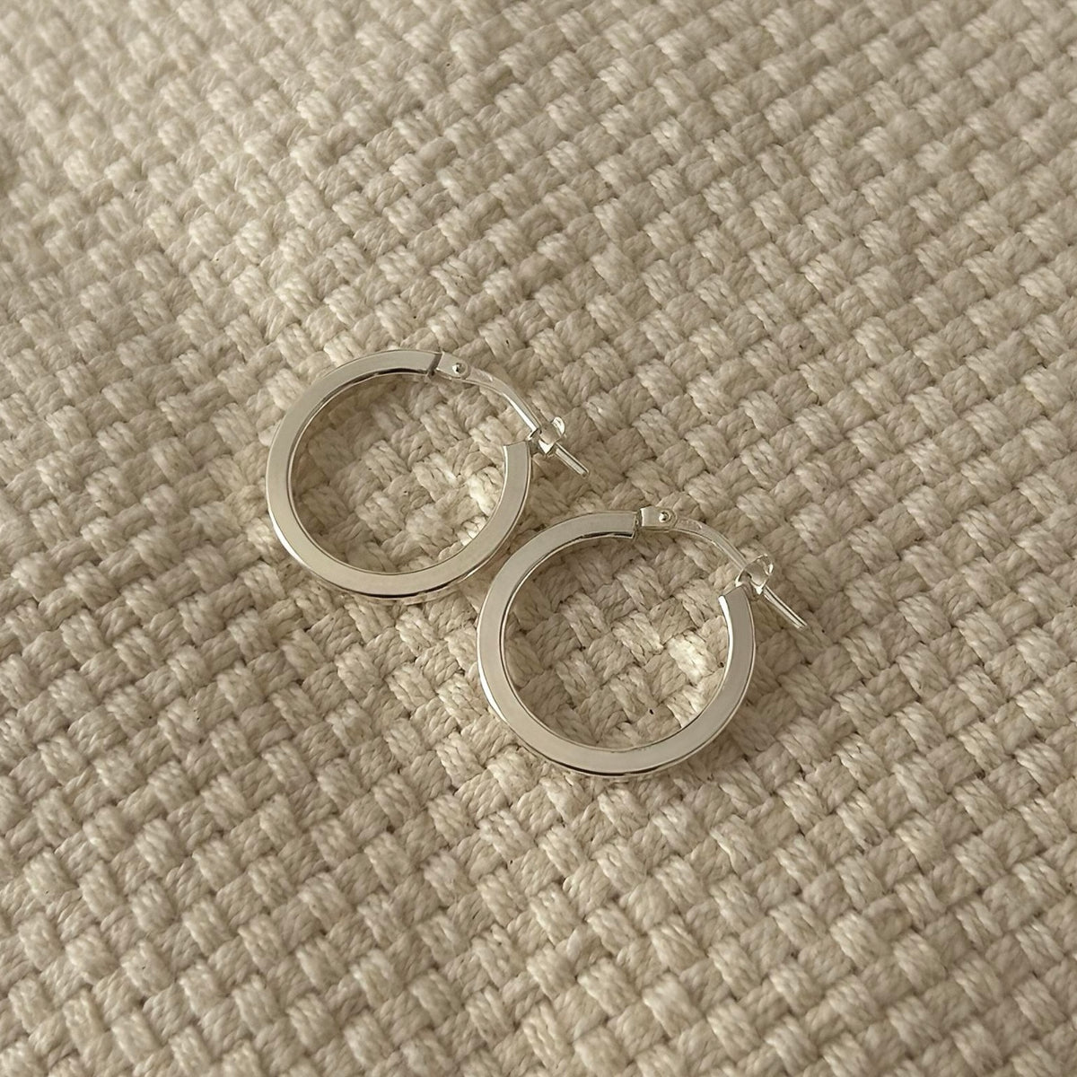 Pair of polished silver hoop earrings, close-up main